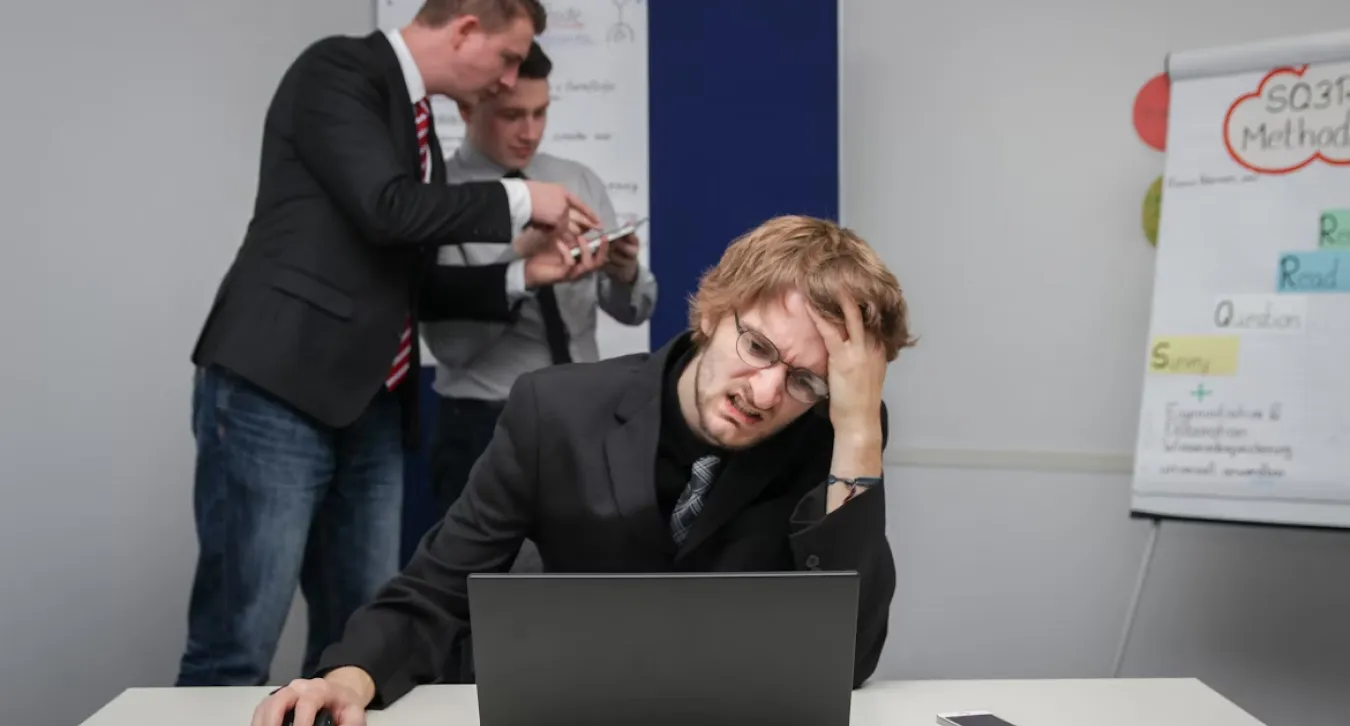 A frustrated worker in an office surrounded by his team