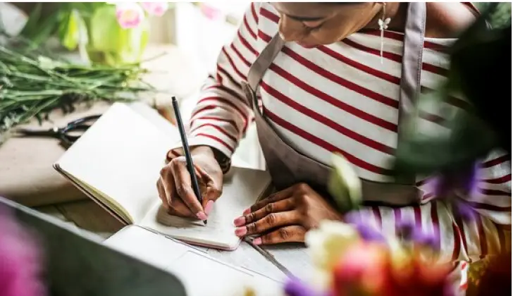 a person writing in a Soft Touch Journal