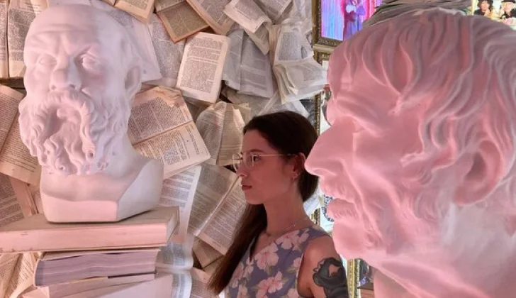 a girl standing in the middle of books and statue