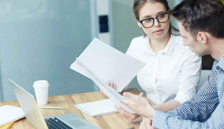 a man and woman checking employee reports