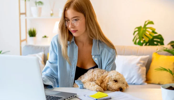 a girl working at home next to her dog