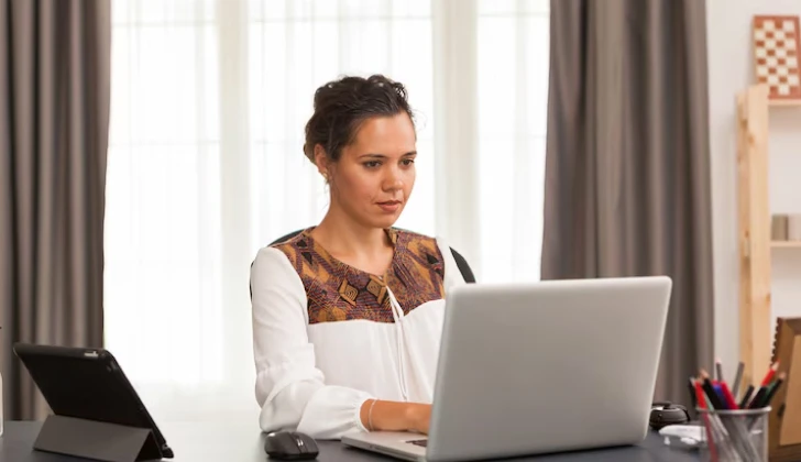 a person typing behind a laptop