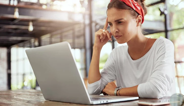 a girl thinking and reading behind laptop