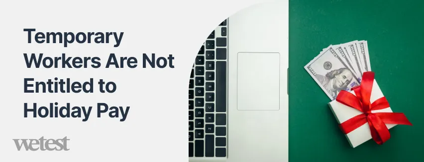 Dollar bills on a desk with a gift on top in front of a laptop