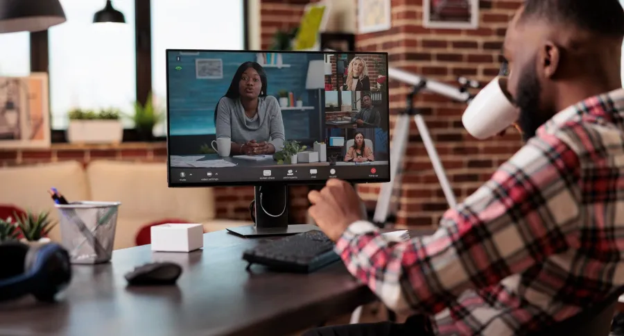 a man sitting in an office, with 4 other people in a virtual meeting